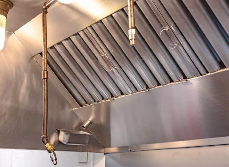 Kitchen hood with suppression nozzles above cooking line