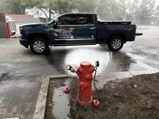 Fire hydrant fitted with pressure gauges during a flow test, First Response truck parked behind
